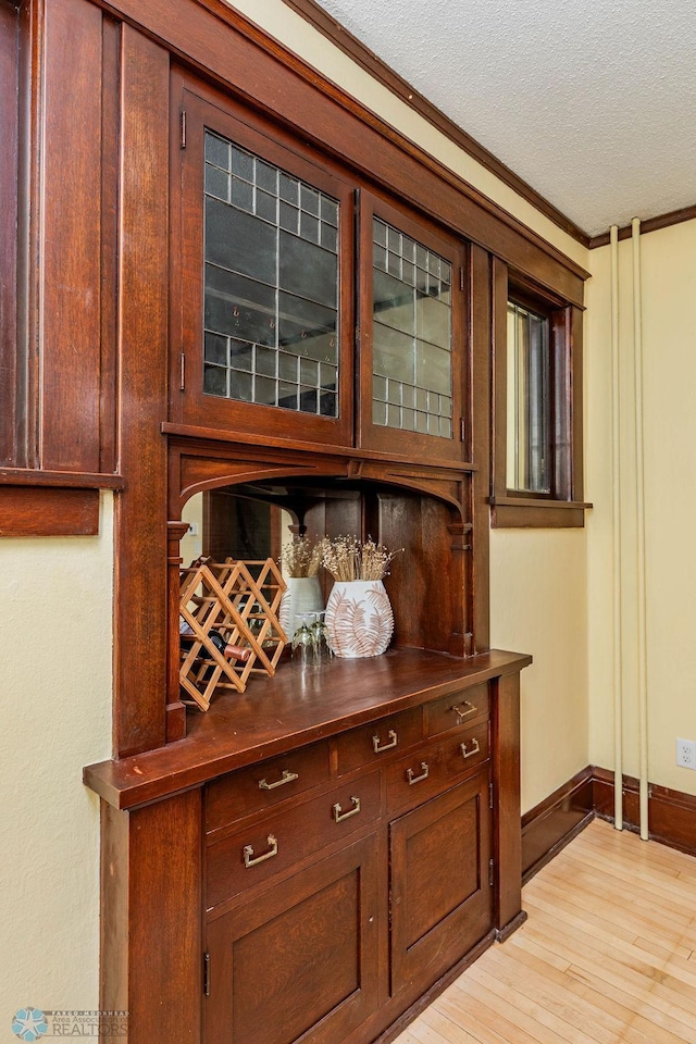 interior details with wood-type flooring, a textured ceiling, and ornamental molding