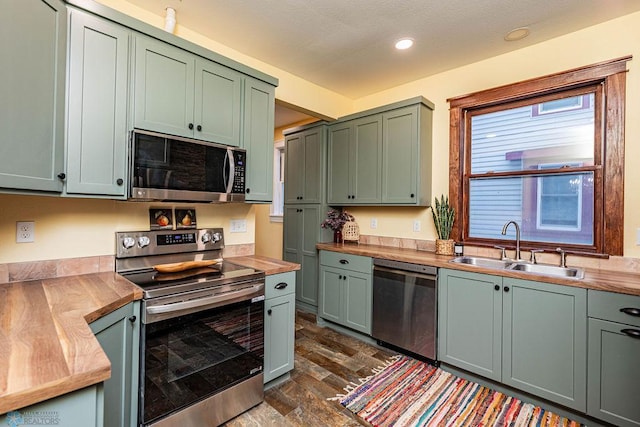 kitchen featuring green cabinets, sink, wood counters, dark hardwood / wood-style floors, and appliances with stainless steel finishes