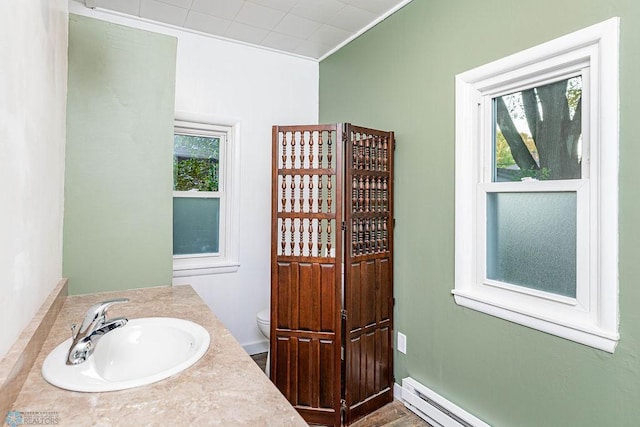 bathroom with vanity, a baseboard radiator, toilet, and a healthy amount of sunlight