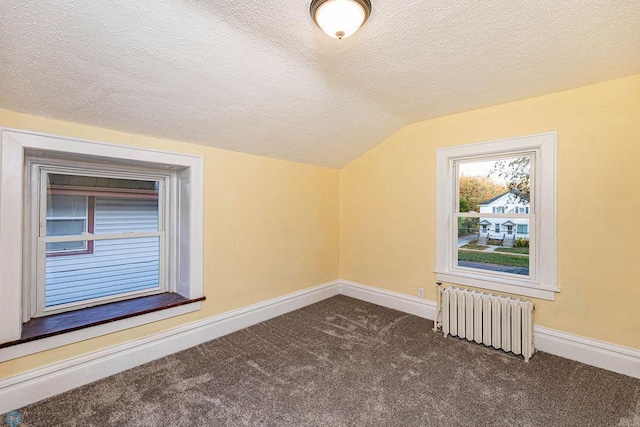 bonus room featuring vaulted ceiling, radiator, dark carpet, and a textured ceiling