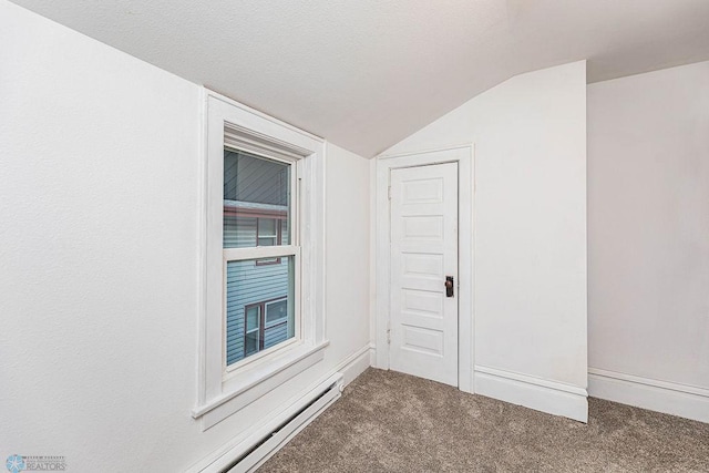 carpeted spare room featuring baseboard heating, vaulted ceiling, and a textured ceiling