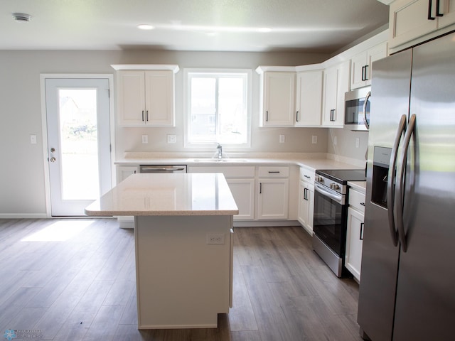 kitchen with stainless steel appliances, a center island, a wealth of natural light, and white cabinetry