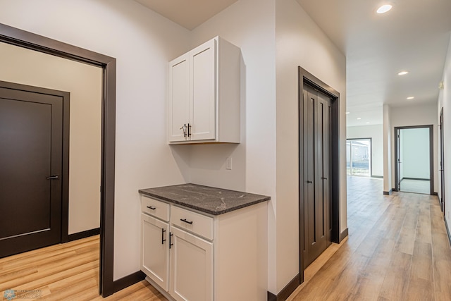 interior space featuring dark stone counters, light hardwood / wood-style floors, and white cabinetry