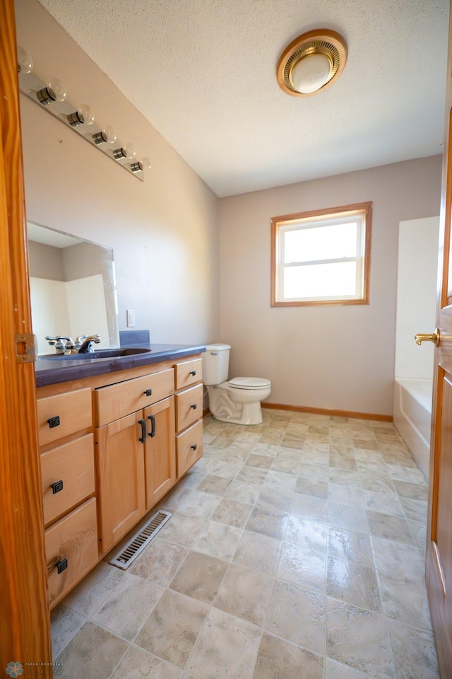 bathroom featuring vanity, a textured ceiling, toilet, and a bath