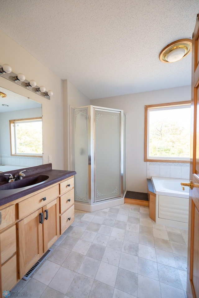 bathroom featuring shower with separate bathtub, vanity, and a textured ceiling