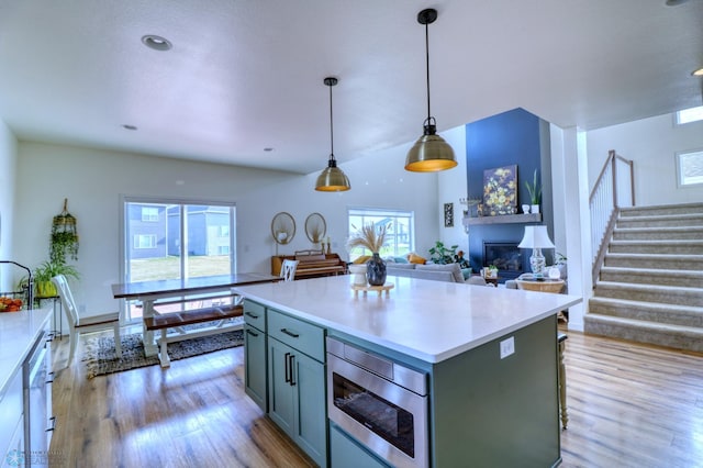 kitchen with appliances with stainless steel finishes, a wealth of natural light, hanging light fixtures, and a center island