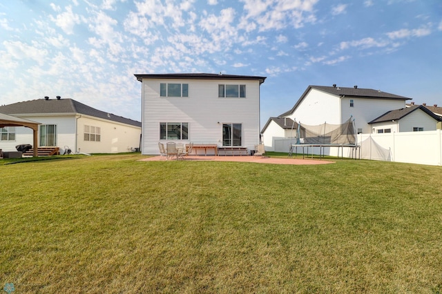 back of property featuring a trampoline, a patio, and a lawn