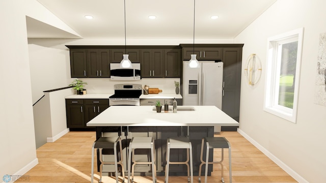 kitchen with light hardwood / wood-style floors, white appliances, decorative light fixtures, vaulted ceiling, and an island with sink