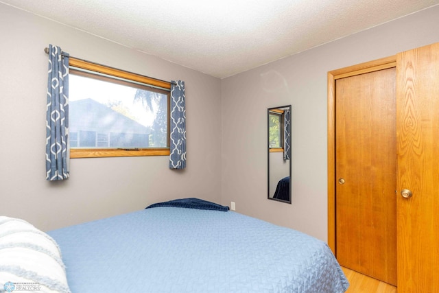 bedroom featuring a closet, hardwood / wood-style flooring, and a textured ceiling