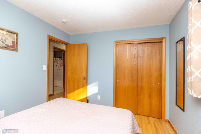 bedroom with a closet, light hardwood / wood-style flooring, and a textured ceiling