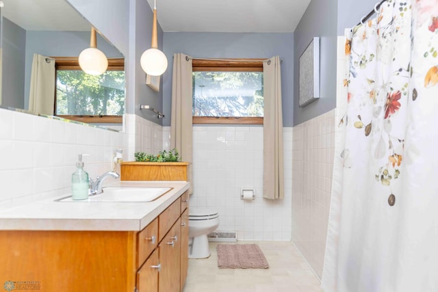 bathroom featuring a wealth of natural light, tile walls, toilet, and vanity