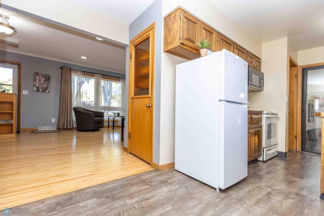 kitchen with light hardwood / wood-style flooring, crown molding, and white appliances