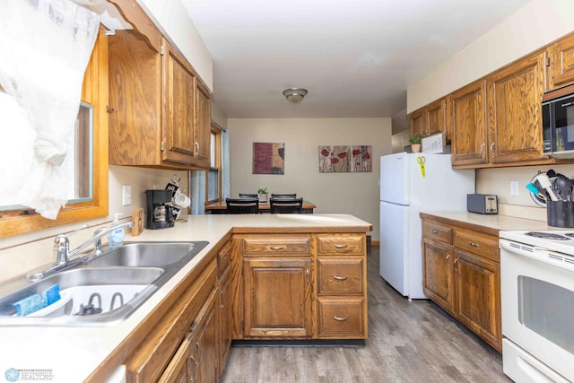 kitchen featuring white appliances, kitchen peninsula, sink, and light wood-type flooring