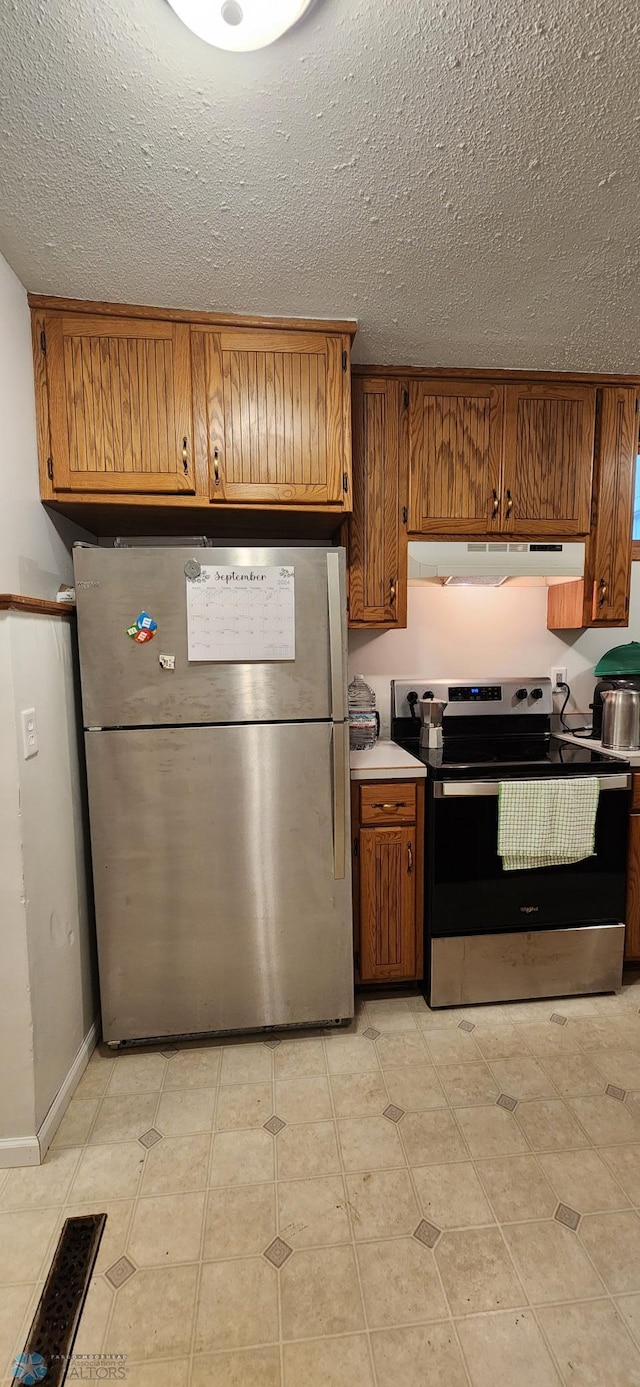 kitchen with appliances with stainless steel finishes, light tile patterned flooring, and a textured ceiling