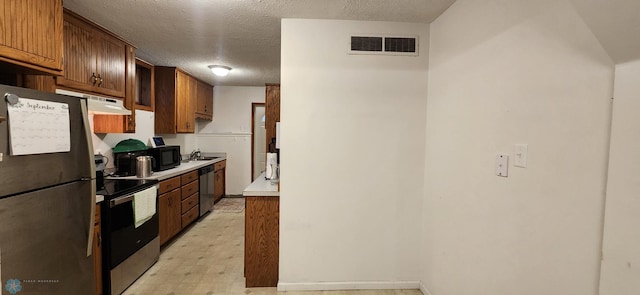 kitchen with appliances with stainless steel finishes, sink, and a textured ceiling