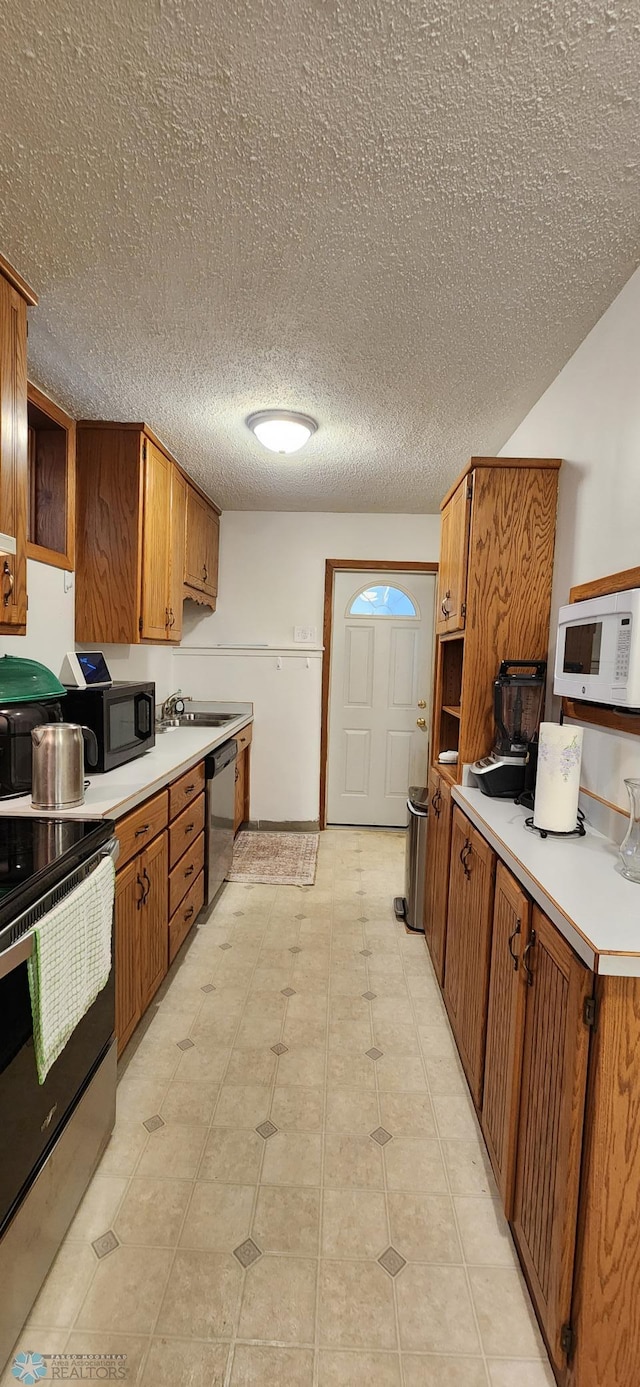 kitchen featuring light tile patterned flooring, appliances with stainless steel finishes, sink, and a textured ceiling