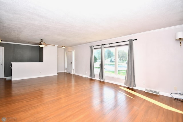 empty room with wood-type flooring, ornamental molding, and a textured ceiling