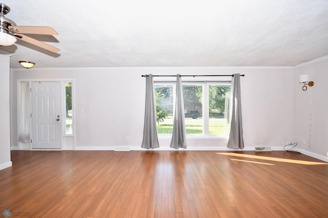 empty room featuring wood-type flooring, a textured ceiling, ornamental molding, and ceiling fan