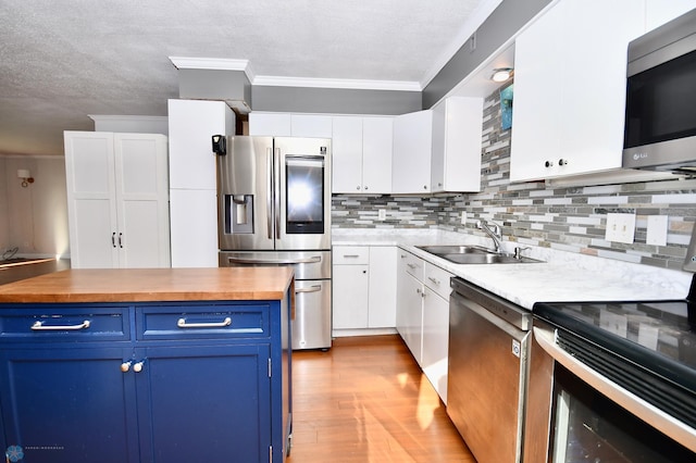 kitchen featuring light hardwood / wood-style floors, blue cabinets, crown molding, stainless steel appliances, and white cabinets