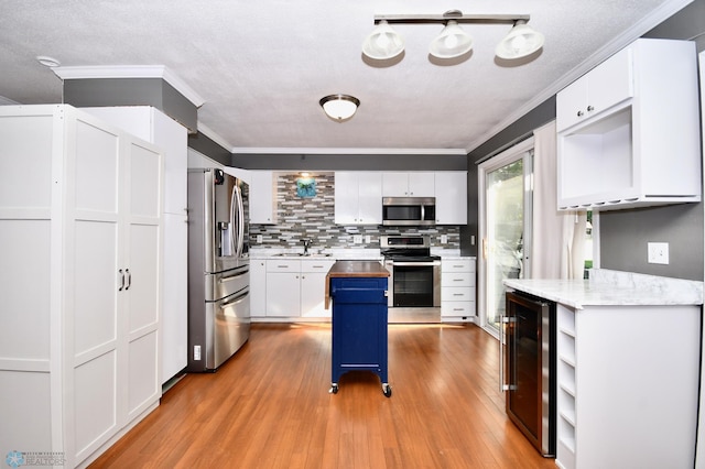 kitchen with a kitchen island, stainless steel appliances, light hardwood / wood-style floors, white cabinetry, and wine cooler