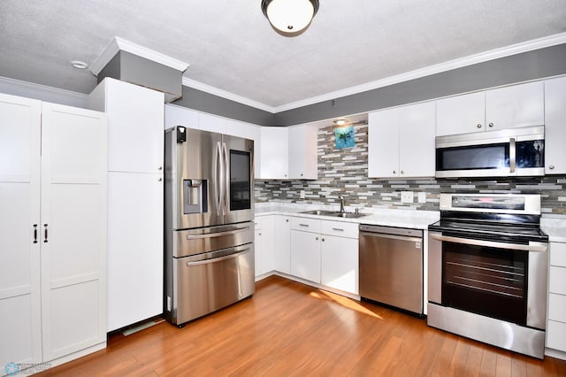 kitchen featuring appliances with stainless steel finishes, light wood-type flooring, sink, and white cabinets