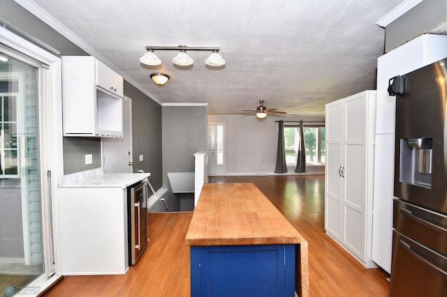 kitchen with light hardwood / wood-style floors, wooden counters, stainless steel refrigerator with ice dispenser, and white cabinetry