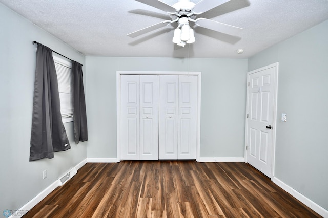 unfurnished bedroom with ceiling fan, a textured ceiling, a closet, and dark hardwood / wood-style floors