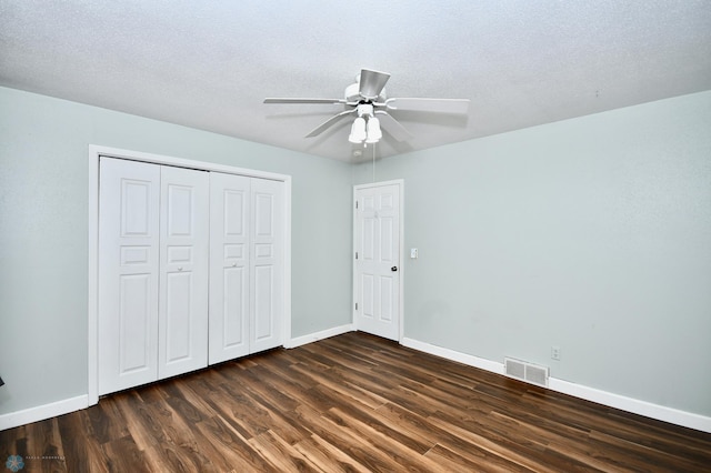 unfurnished bedroom with ceiling fan, a textured ceiling, and dark wood-type flooring