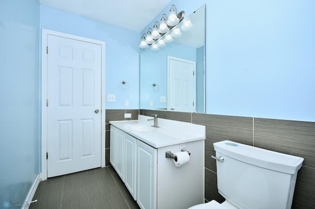 bathroom featuring vanity, tile walls, and toilet