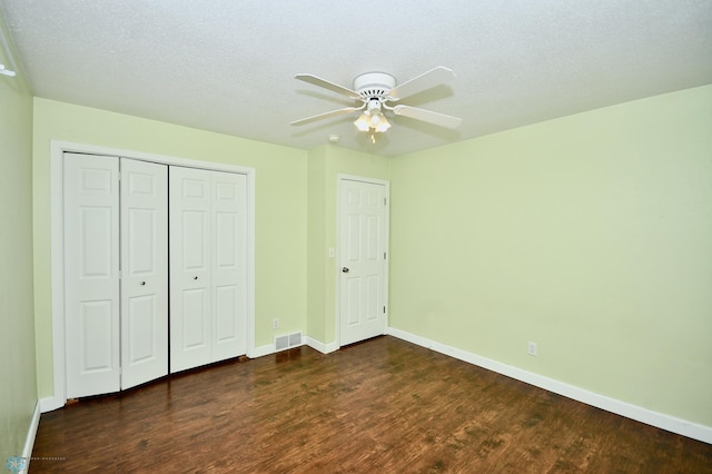 unfurnished bedroom with dark hardwood / wood-style flooring, a textured ceiling, and ceiling fan