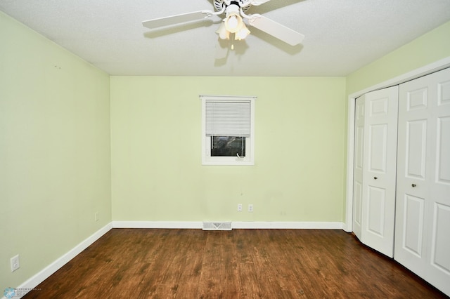 unfurnished bedroom with ceiling fan, a textured ceiling, a closet, and dark hardwood / wood-style flooring