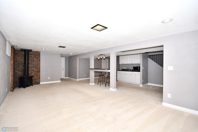 unfurnished living room featuring light carpet and sink