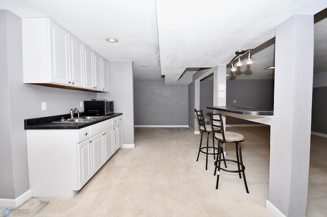 kitchen featuring light carpet, a breakfast bar area, sink, and white cabinetry