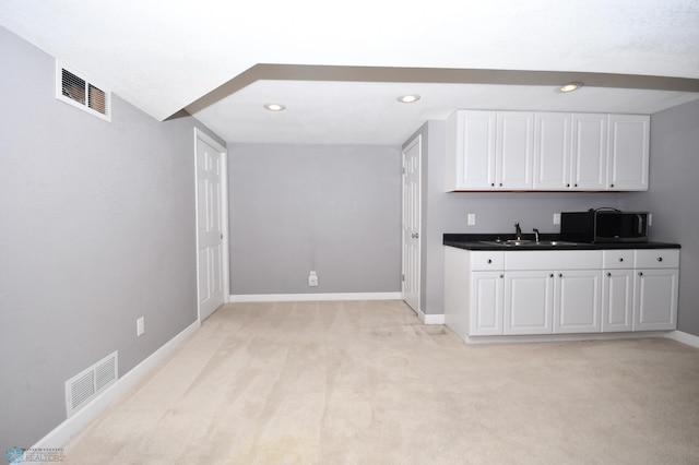 kitchen featuring light colored carpet, sink, and white cabinets