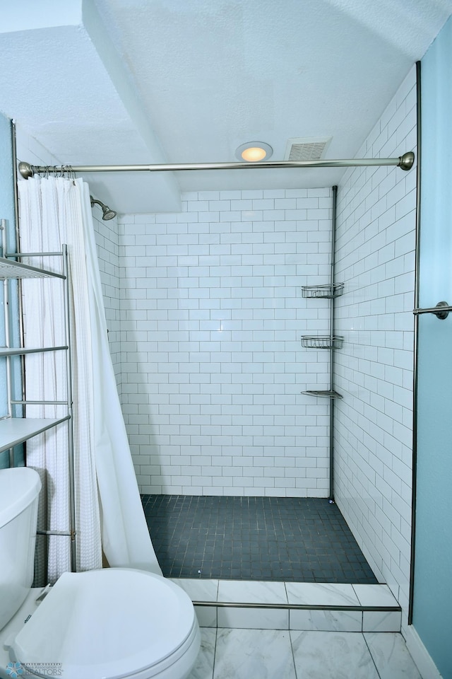 bathroom featuring a textured ceiling, toilet, and a shower with shower curtain