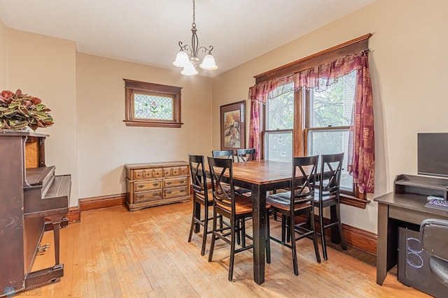 dining space with a notable chandelier, light wood-type flooring, and a wealth of natural light