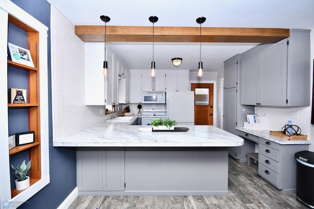 kitchen with tasteful backsplash, dark wood-type flooring, white appliances, kitchen peninsula, and decorative light fixtures