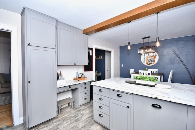 kitchen featuring pendant lighting, light hardwood / wood-style flooring, gray cabinets, light stone countertops, and decorative backsplash