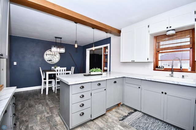 kitchen with beamed ceiling, sink, dark hardwood / wood-style flooring, kitchen peninsula, and decorative light fixtures