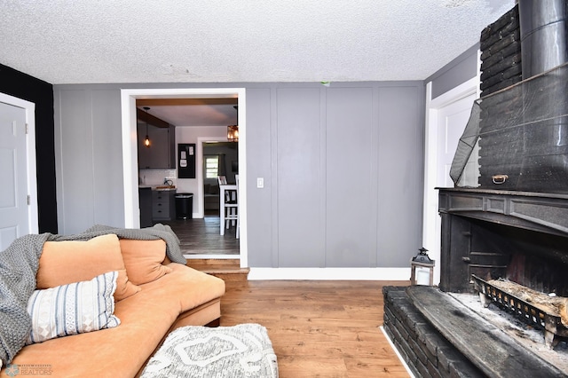 living room featuring wood-type flooring, a textured ceiling, and a fireplace