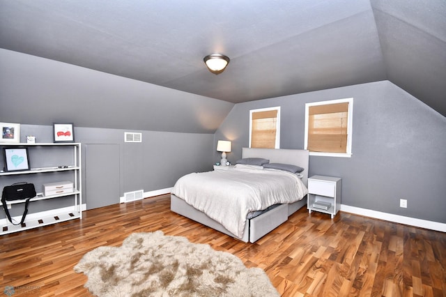 bedroom featuring hardwood / wood-style flooring, vaulted ceiling, and a textured ceiling