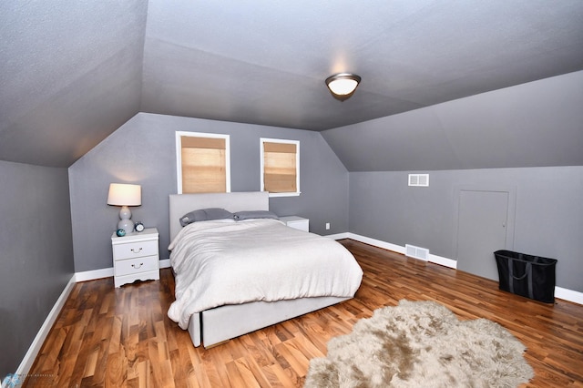 bedroom featuring a textured ceiling, lofted ceiling, and dark hardwood / wood-style flooring