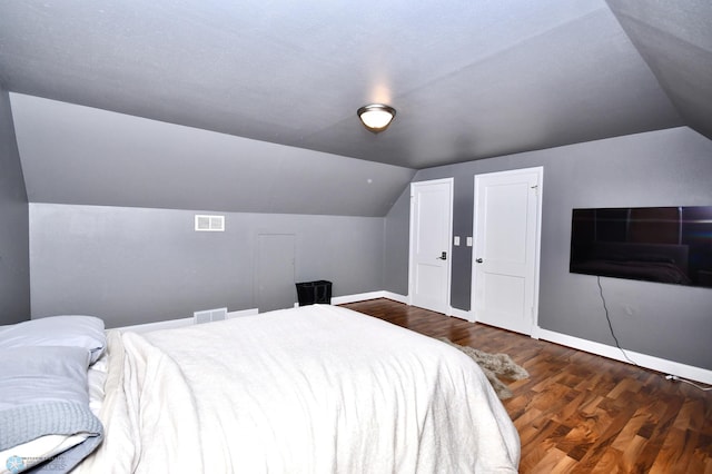 bedroom with a textured ceiling, lofted ceiling, and dark hardwood / wood-style flooring