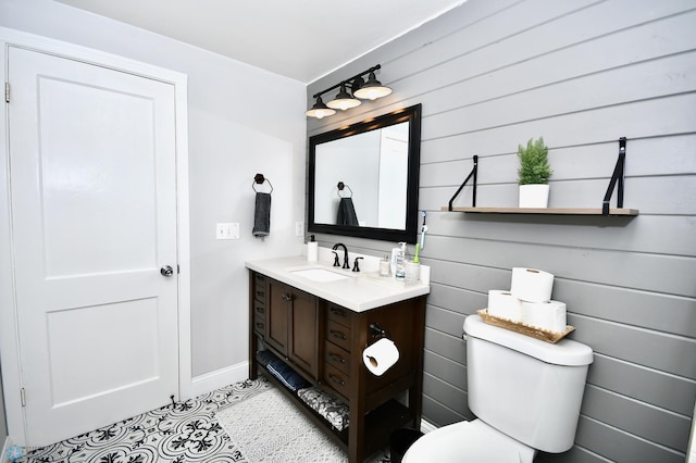 bathroom featuring wooden walls, vanity, and toilet