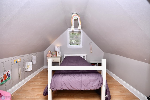 bedroom with lofted ceiling and light hardwood / wood-style floors