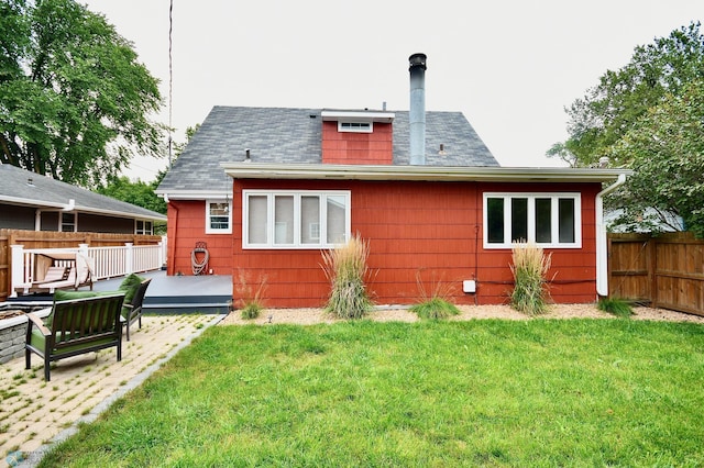 back of property with a deck, a lawn, and a patio area