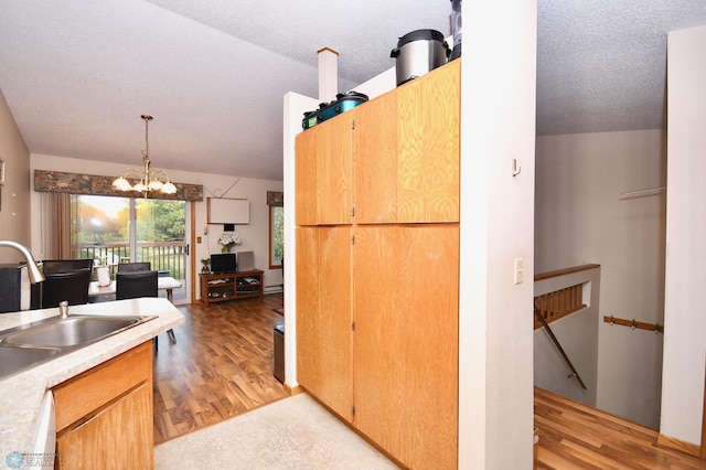 kitchen featuring a textured ceiling, light wood-type flooring, hanging light fixtures, and a chandelier