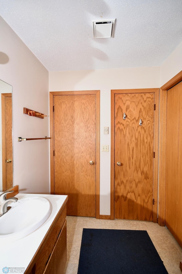 bathroom with tile patterned floors, vanity, and a textured ceiling