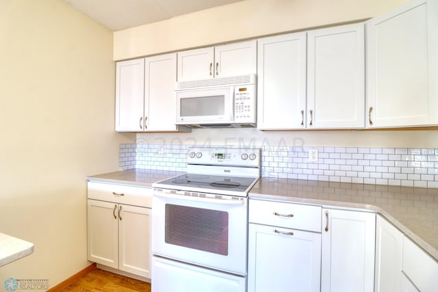 kitchen with white appliances, tasteful backsplash, white cabinetry, and light hardwood / wood-style flooring