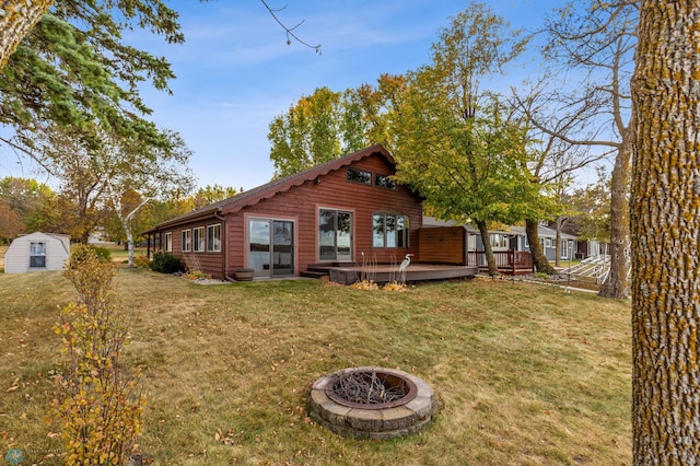 exterior space featuring a storage unit, a deck, a fire pit, and a lawn